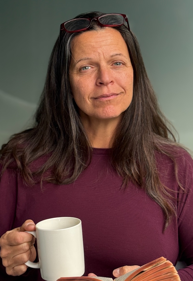Becs Zelis holding a book and a white mug
